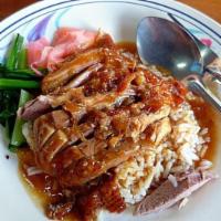 Roasted Duck Over Rice · Roasted duck with brown gravy sauce, watercress and sweet ginger over rice.