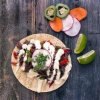 Carne Asada Taco · Caramelized Onions and Peppers, Topped With Radish, Cilantro and Jalapeño Cilantro Crema