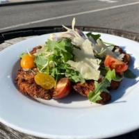 Chicken Milanese · Breaded chicken cutlet topped with arugula, heirloom tomatoes, red onions, shaved parm, lemo...