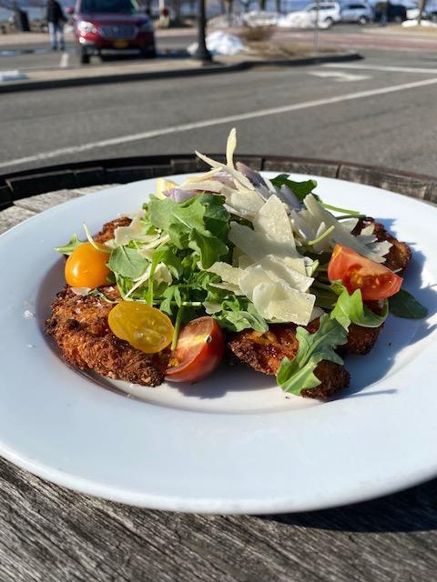 Chicken Milanese · Breaded chicken cutlet topped with arugula, heirloom tomatoes, red onions, shaved parm, lemon, olive oil