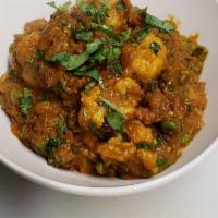 31. Aloo Gobi Muttar · Onion, tomato based curry with potatoes, cauliflower and green peas. Served with rice and pe...