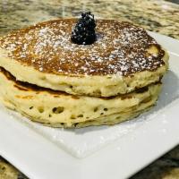 Ovo Pancakes · Three pancakes dusted with powdered sugar and served with pancake syrup.