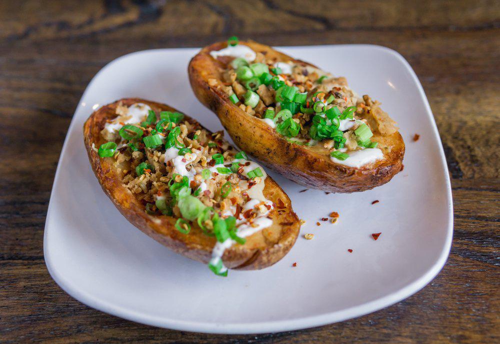 Loaded Potato Skins · A single potato, cut in half and loaded up with crispy tempeh bacon, melted cheese, sour cream and chives. 