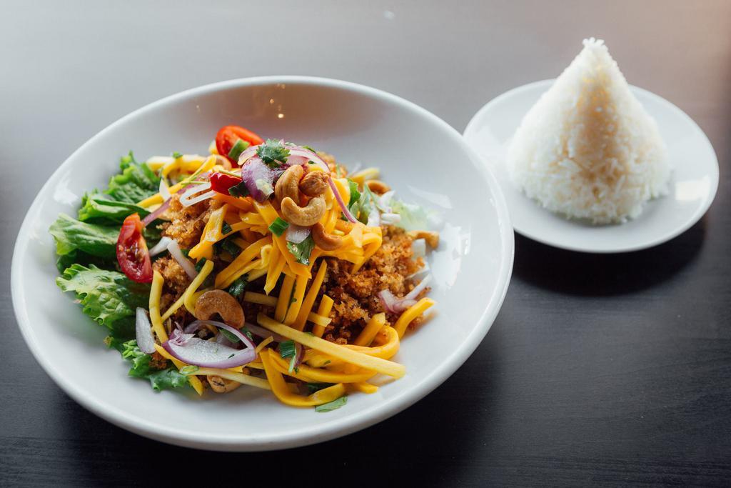 SP1. Crispy Catfish Salad · Shredded catfish meat, battered and deep-fried topped with mango salad, red onions, cashew nuts, scallions, tomatoes with lime-chili dressing. Served with jasmine rice. Spicy.