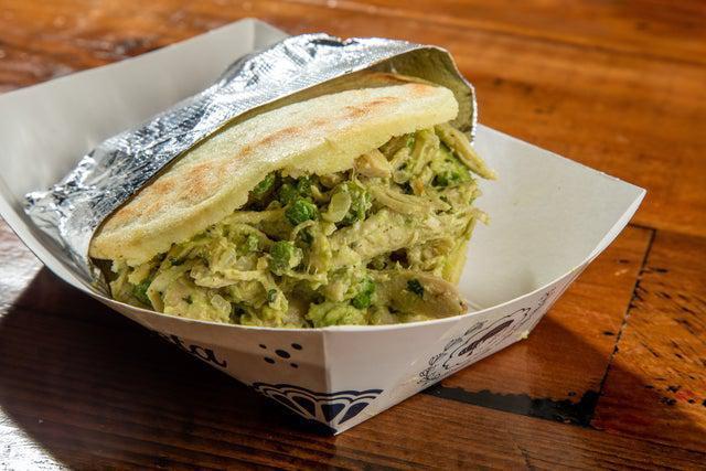 Arepa Reina Pepiada · Origin: Andes, Venezuela. Cooked ground maize dough shaped into a thick disc, stuffed with shredded chicken salad (Avocado, sweet peas, mayo, and spices).