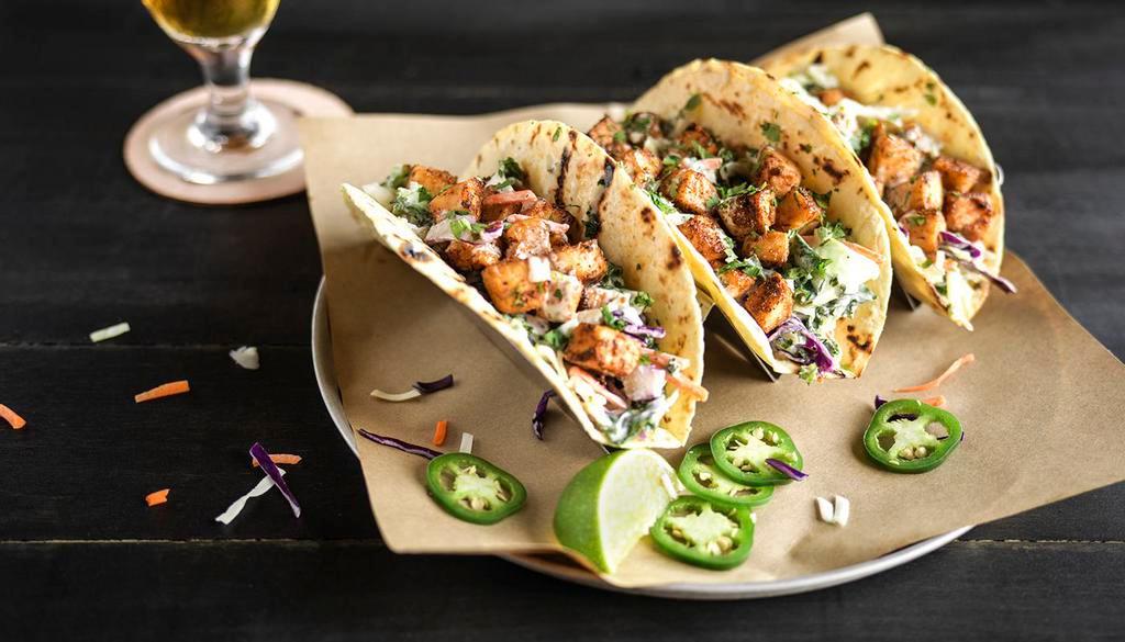 Mahi Mahi Tacos · Blackened Mahi Mahi served over coleslaw, in a grilled tortilla, drizzled with house-made tartar sauce and topped with fresh cilantro.