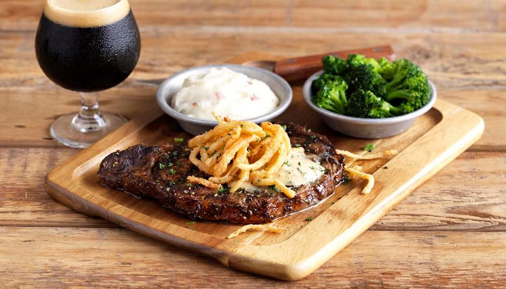 Ribeye · 12 oz. USDA Choice Ribeye seasoned & grilled topped with Stout butter & fried onions, served with red skin mashed potatoes & steamed broccoli.