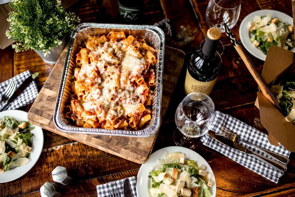 Rigatoni with Italian Sausage Family · Baked rigatoni with Italian sausage, caesar salad with dressing on the side, loaf of italian bread, and vanilla cheesecake to share.