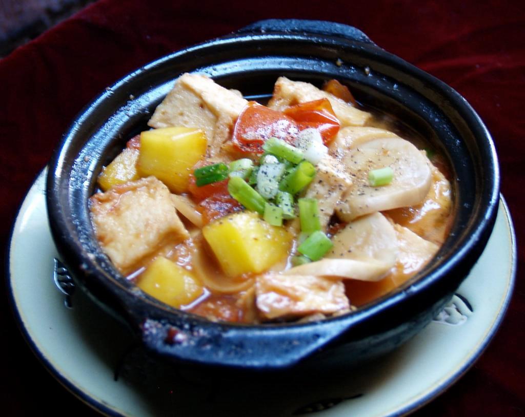 55. Tofu Stew in Clay Pot  · Tau hu kho to. Stew in clay pot with garlic, tofu, mushroom, tomato, and pineapple. Topped with green onions and black pepper. Gluten free.