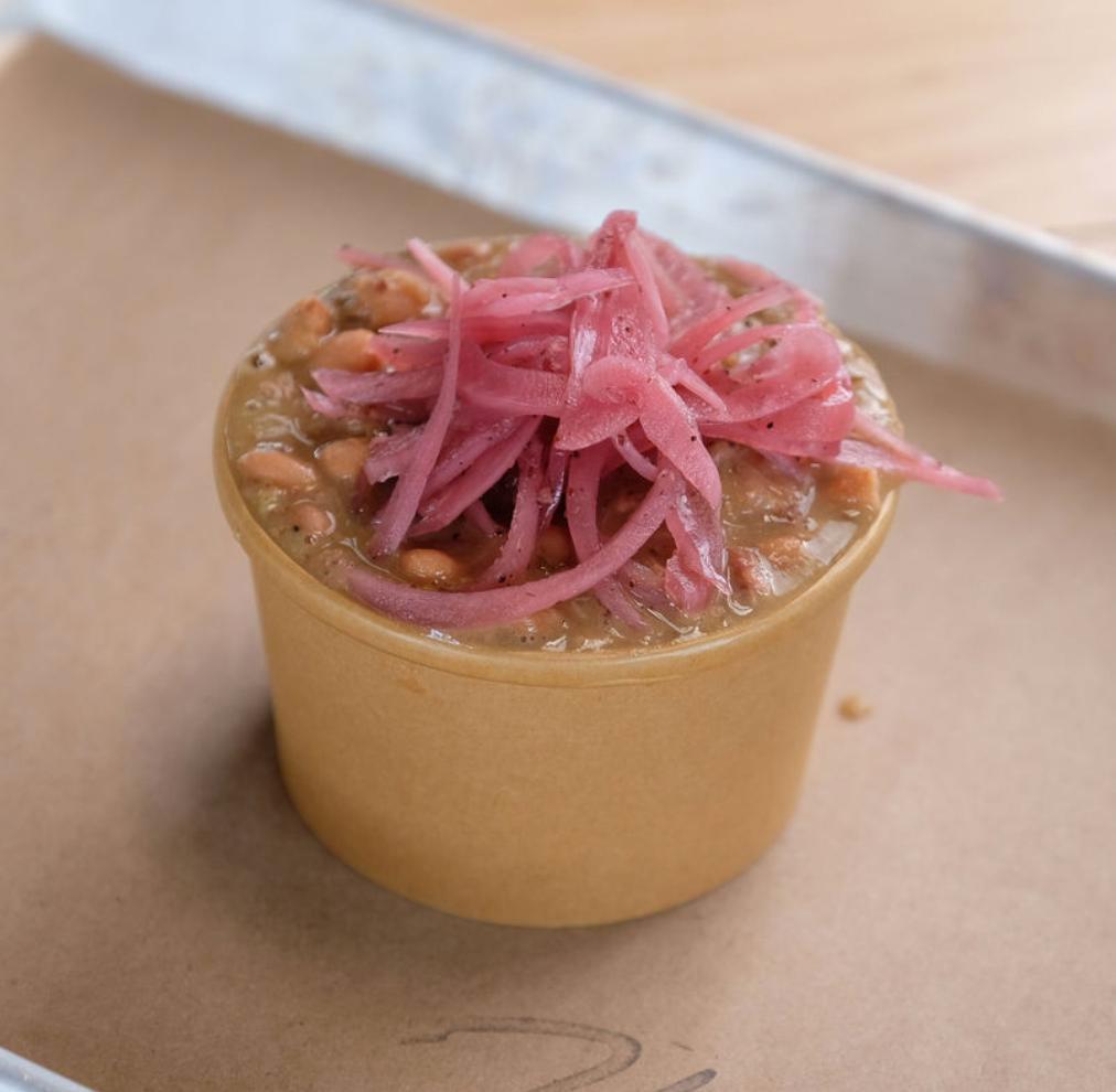 Beans · Peppery pinto beans stewed with smoked pork stock, topped with pickled red onions.