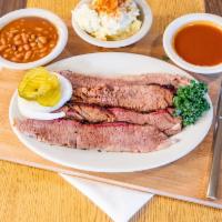 Beef Brisket · Sliced brisket with sauce, pickles, onion, baked beans and potato salad.