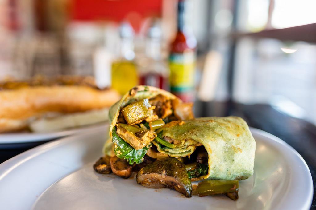 Roasted Veggie Wrap · Oven Roasted Red Onions, Green Peppers, Zucchini, Eggplant and sauteed Spinach with a caribbean flair paired with Hummus in a Spinach Tortilla.