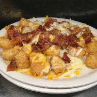 Smothered Tots · Served with Swiss, cheddar, bacon, and sour cream.