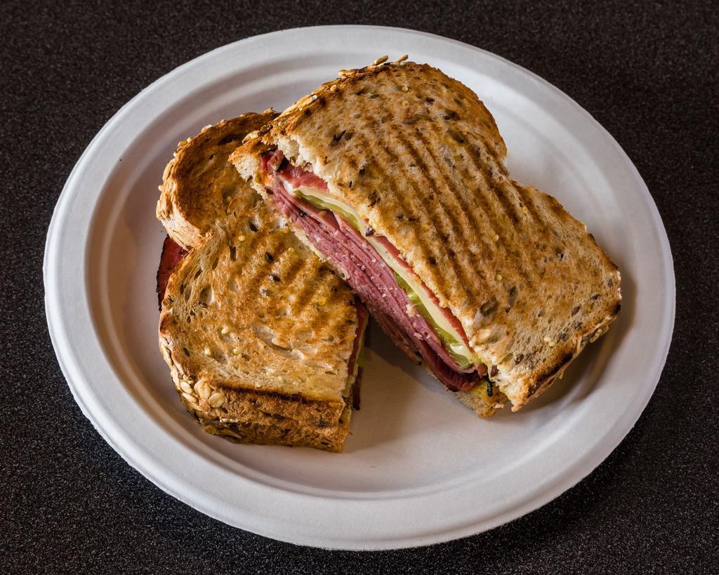 Pickled Pastrami Panini Sandwich · Sliced hot pastrami, topped with melted swiss cheese, sliced pickle and dijon mustard on wheat bread panini style. 