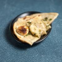Garlic Bread · Topped with fresh garlic and cilantro. Baked fresh, on the interior wall of the tandoor (cla...