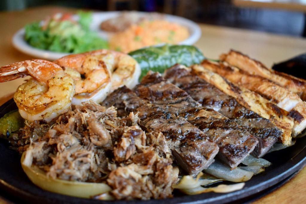 Habanero Platter · A sizzling platter of marinated chicken, tender inside skirt steak, shredded carnitas and 3 marinated grilled shrimp, served over sauteed onions and bell peppers. Served with guacamole, pico de gallo and warm tortillas. No substitutions.