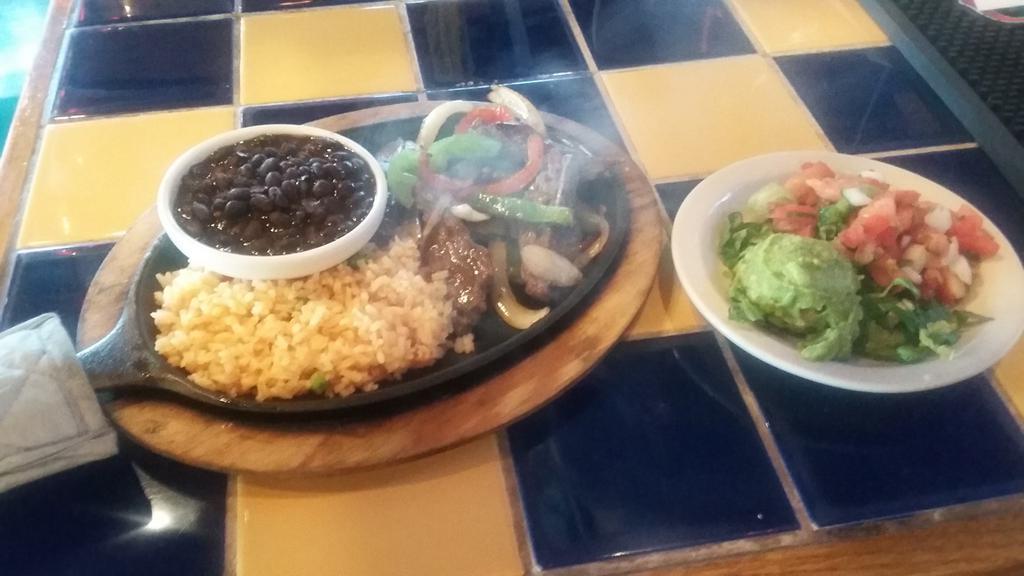 Baja Fajitas · A sizzling skillet of marinated chicken or combination inside skirt steak and chicken, sauteed with fresh bell peppers and onions. Served with charro beans, rice, guacamole, pico de gallo and warm tortillas.