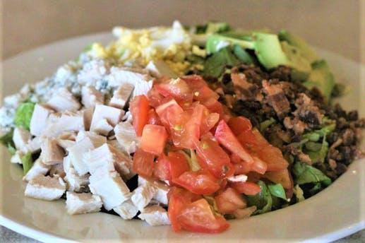 Cobb Salad · Fresh Roasted Turkey breast, fresh avocado, sugar cured bacon, bleu cheese crumbles with diced tomato and egg over a bed of fresh greens
