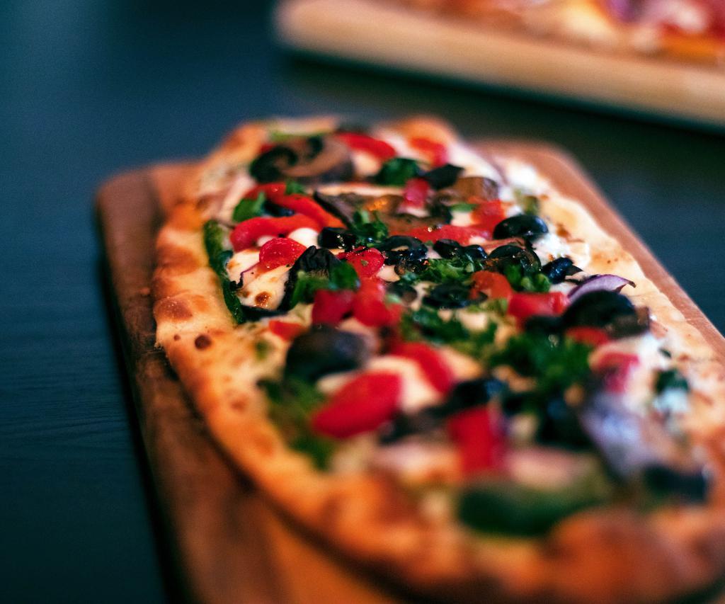 Veggie Flatbread Pizza · Basil pesto, mozzarella, Parmesan-Romano cheese, red bell peppers, red onions, crimini mushrooms, spinach and sliced black olives.