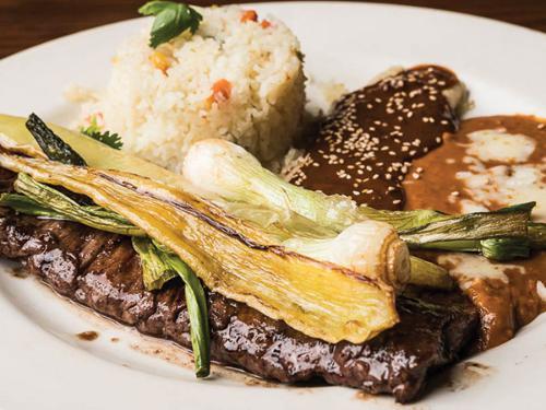 Carne Asada Tampiquena · Carne asada a la tampiquena. Choice skirt steak. Served with cheese enchilada topped with Mexican cheese, sauteed onions, tomatoes, mushrooms and mole poblano sauce.