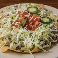 Nachos Santo Coyote · Ground beef, chicken, beans, pickled jalapenos, lettuce, tomato, sour cream and queso dip ov...