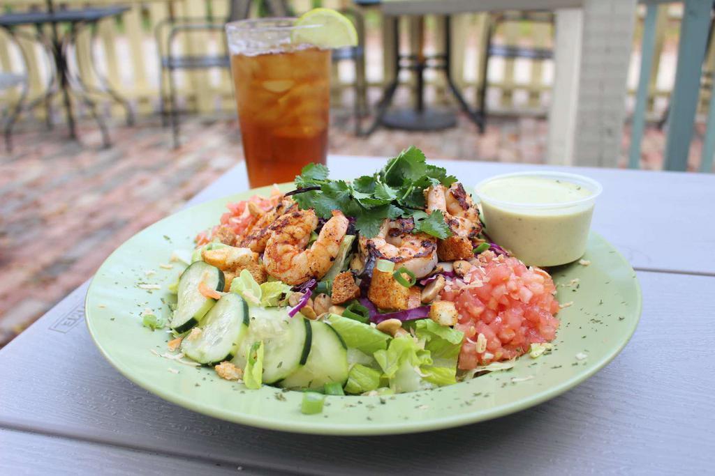 Shrimp Curry Salad · Cajun grilled shrimp over chopped romaine, shredded red and carrots, diced tomatoes, marinated cucumbers, toasted coconut, roasted cashews and croutons, topped with green onions and cilantro and served with our buttermilk coconut curry dressing. Gluten-free. 
