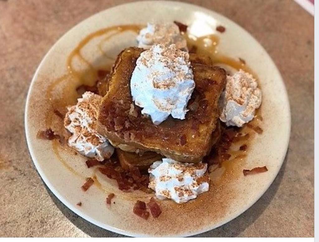 Cinnamon Caramel French Toast Breakfast · 3 slices of French toast served in a bowl with crumbled bacon topped with hot caramel and whipped cream dusted with cinnamon.