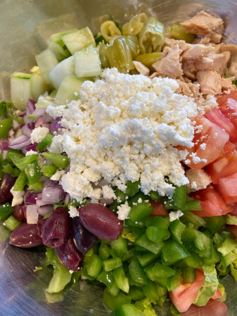 Greek Chicken Salad · Grilled chicken, Romaine lettuce, Kalamata olives, feta cheese, onions, tomatoes, cucumbers, salonika peppers, green peppers, Greek vinaigrette dressing.