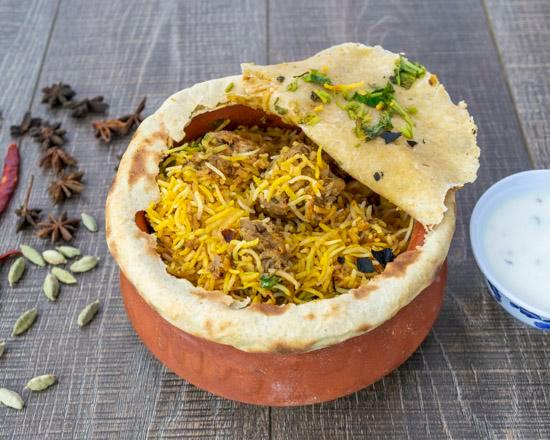 Goat Dum Biryani · Hyderabadi style spicy goat on the bone with basmati rice served in a dough sealed pot.