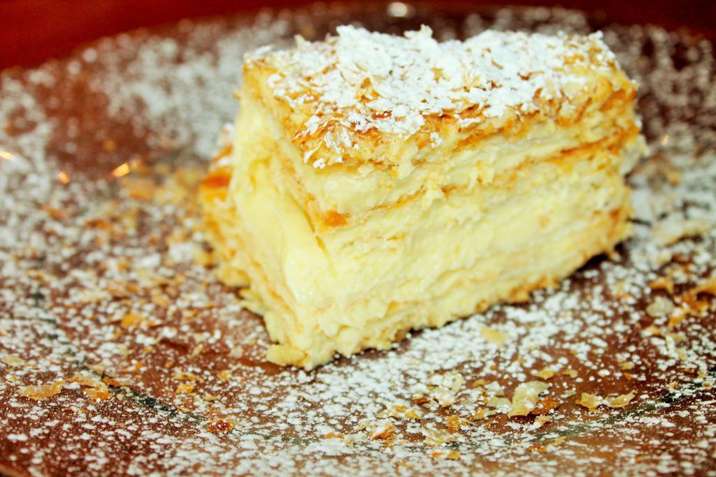 Russian Napoleon · Layers and layers of puff pastry and sweet vanilla bean pastry cream, topped with confectioners sugar.