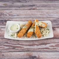 Venezuelan Tequenos · Large, lightly breaded cheese sticks topped off with cilantro cream and queso fresco.