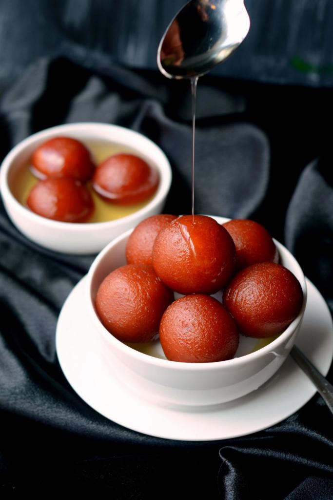 Gulab Jamun · Traditional deep-fried milk pastry served in rosewater honey syrup with a sprinkle of crushed pistachios.