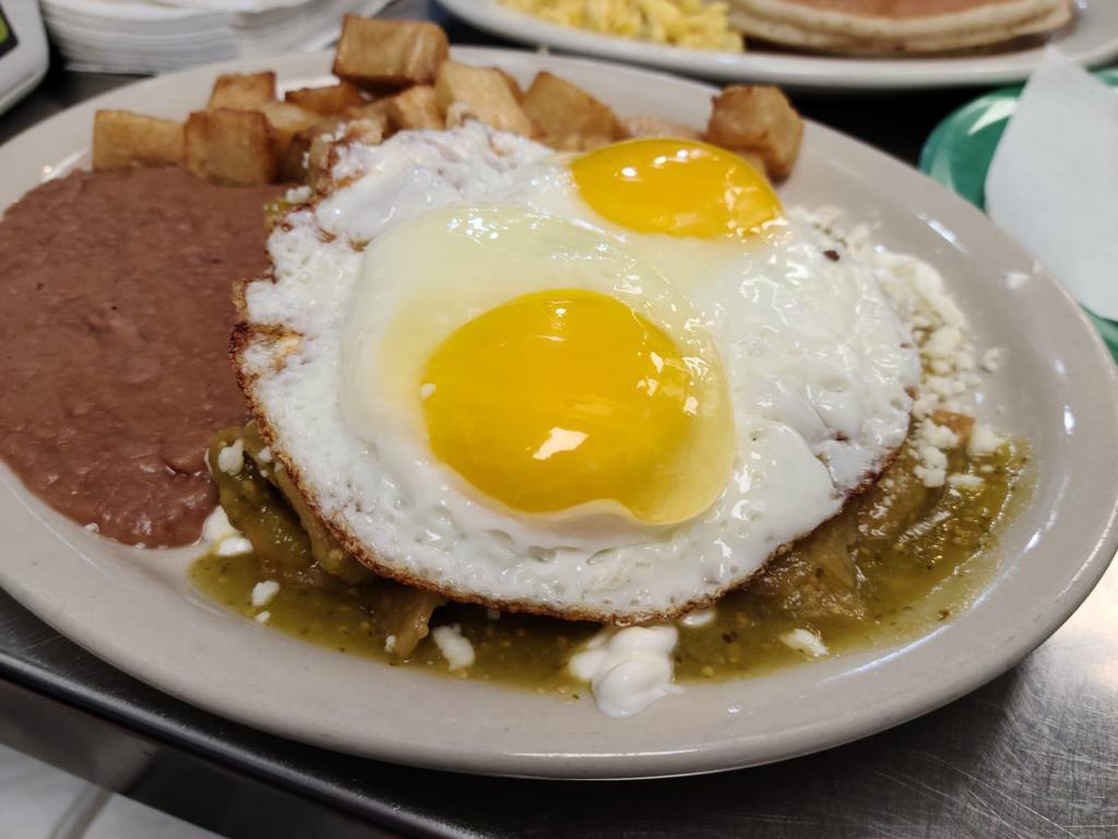 Chilaquiles with Eggs · Tortilla chips with sauce of your choice, queso fresco, sour cream and two eggs on top, served with refried beans, breakfast potatoes and 2 tortillas on the side .