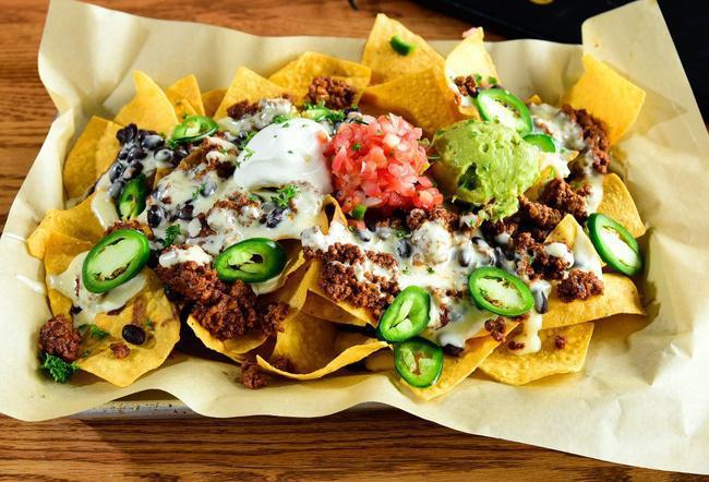 East Village Nachos · Loaded with queso, black beans, sour cream, pico de gallo, jalapenos, house guac, and your choice of chicken, freshly ground beef or vegetarian