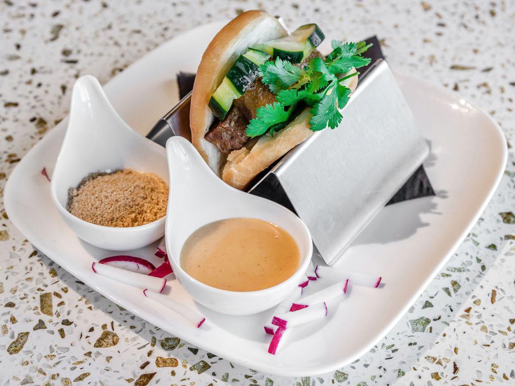 Bao Slider · 1 piece. Fried Asian bun filled with choice of protein, pickled cucumbers, and cilantro. Served with ground peanuts and yum yum sauce on the side.