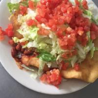 Indian Taco Salad · Fry bread topped with whole beans and ground beef, melted cheese, lettuce, tomato, on a frie...
