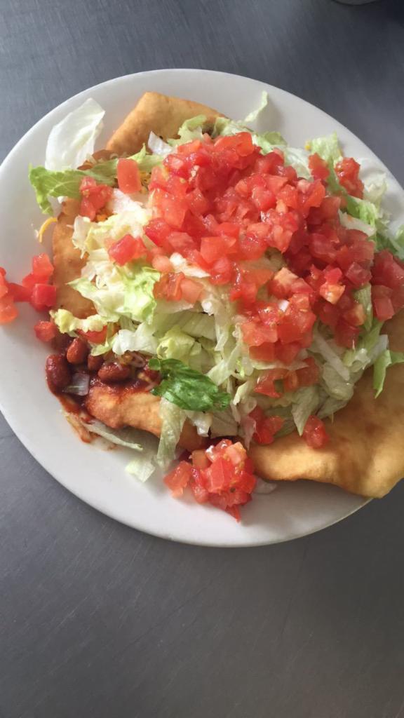 Indian Taco Salad · Fry bread topped with whole beans and ground beef, melted cheese, lettuce, tomato, on a fried bread




