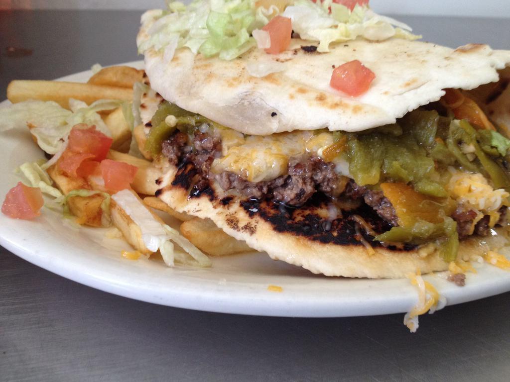 Torta Burger · Homemade flour tortilla folded with a ground beef patty, smothered with red or green chile, cheese and garnish.