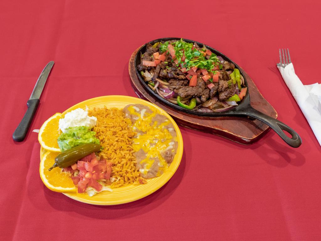 Beef Fajitas · Tender strips of our marinated flank steak, sauteed with bell peppers, onions, and tomatoes. Garnished with sour cream and guacamole.