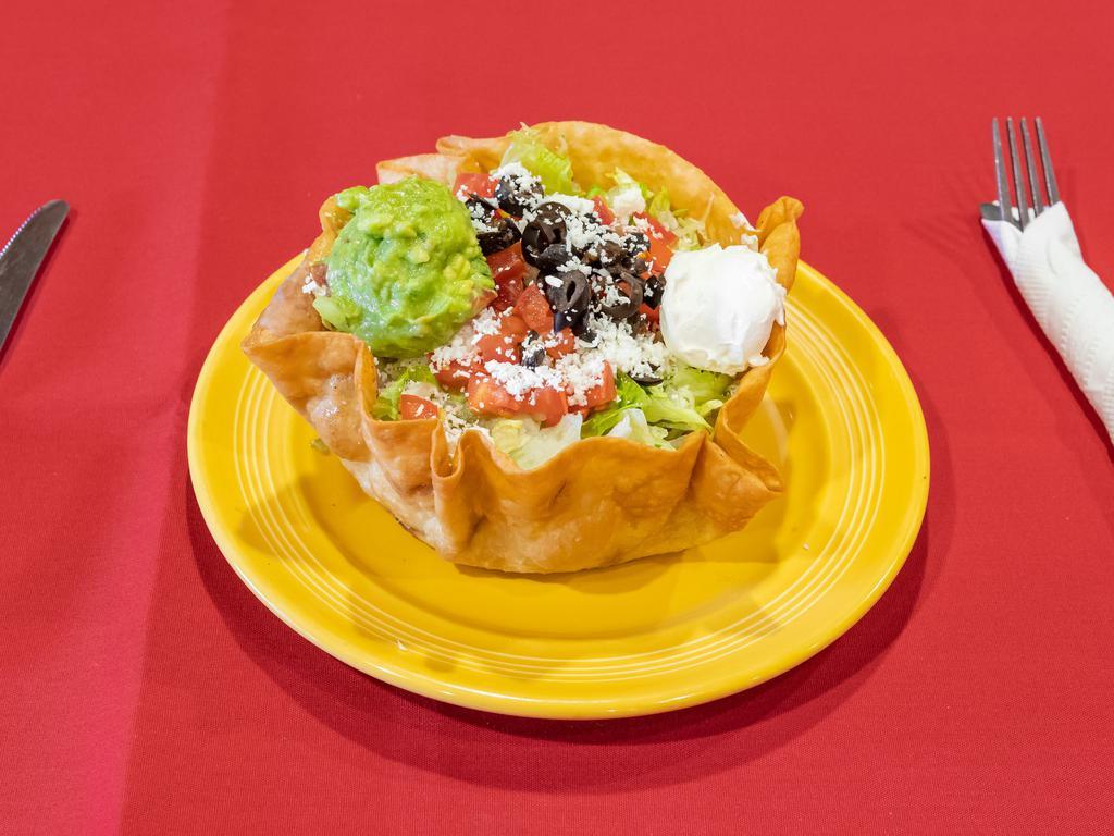 Taco Salad · Thin layer of beans, the meat of your choice, shredded lettuce, queso fresco, tomatoes, sour cream and guacamole. Served in a fried taco shell.