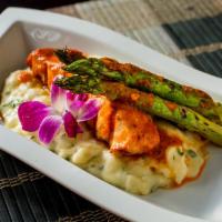 Salmon a la Parrilla · Grilled salmon served with cassava puree and asparagus in a roasted red pepper sauce.