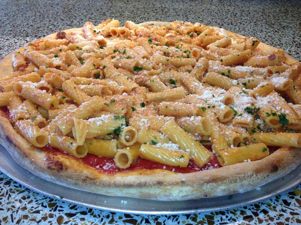 Rigatoni alla Vodka Pizza · Rigatoni sauteed with onions and prosciutto in a pink vodka cream sauce on top of a crispy pizza crust.