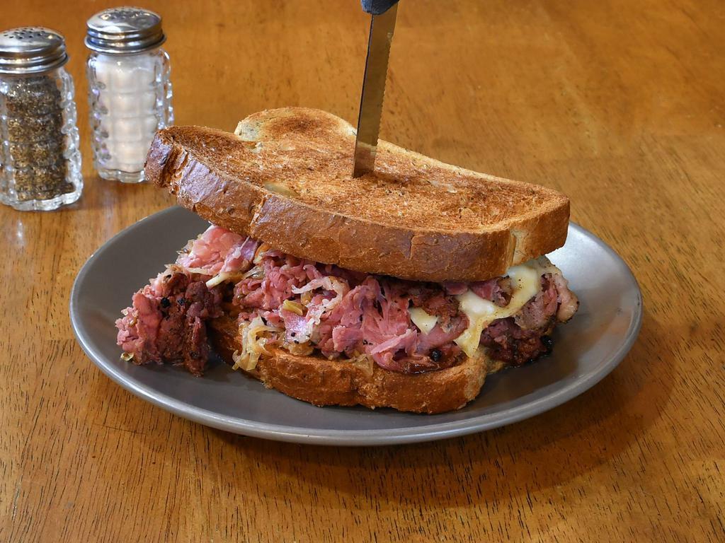 Grilled New York Style Reuben Sandwich · 100 year old German-recipe sauerkraut, pastrami, Swiss, and house mustard on toasted New York rye bread.