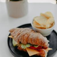 Croissant Breakfast Sandwich · Toasted croissant, garlic aioli, bacon, cheddar cheese, fried egg, avocado, tomato and spina...