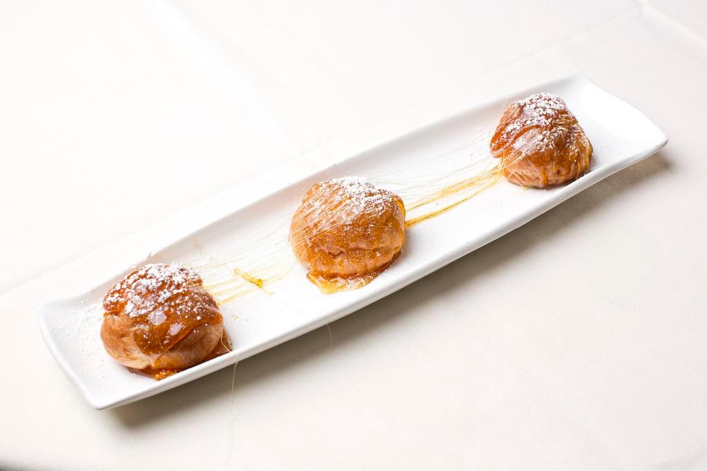 Croquembouche au Caramel · Signature. Stuffed choux with fine grand marnier French vanilla cream, topped with fresh blond caramel, and sliced toasted almond.