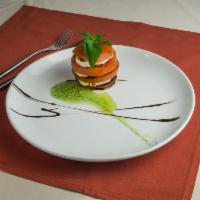 Caprese Tomatoes · Layers of tomato, fresh basil, and mozzarella with pesto and aged balsamic.