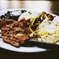 Steak Alebrije Dinner · Thin sliced steak served with rice, beans, esquites, rajas, and guacamole.