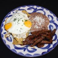 Chilaquiles · Fried egg, carne asada and fried corn tortillas with refried beans, onions, queso fresco, so...