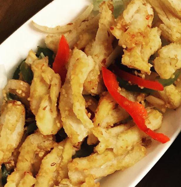 Spicy Squid (GF) · Lightly breaded squid stir fry with bell pepper, onion, garlic and spice over a bed of lettuce.