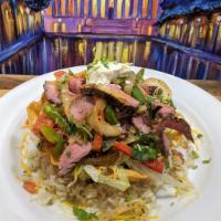 Grilled Steak Taco Salad · A Crispy Flour Tortilla bowl on a bed of Rice, filled with slices of grilled Steak, choice o...